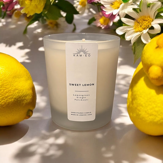 A candle in a frosted glass with a label that says “sweet lemon”